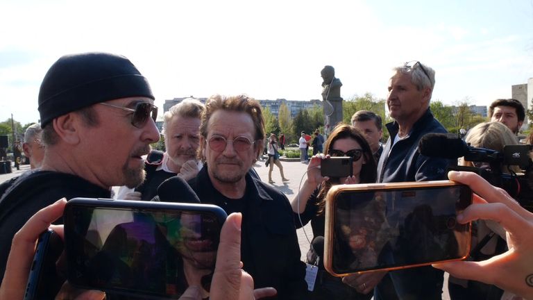 U2's The Edge speak to reporters in Borodyanka, as bandmate Bono and Sky News's Mart Austin look on